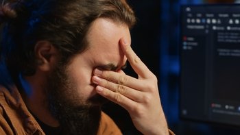 Disappointed computer scientist puzzled after being unable to remove all bugs while coding on workstation desktop. Teleworking IT specialist confused by troubling script errors, camera A close up